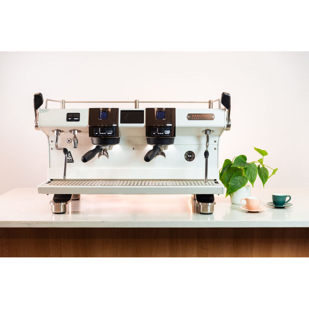 White Rancilio RS1  two group head espresso machine on bar with cups and plant